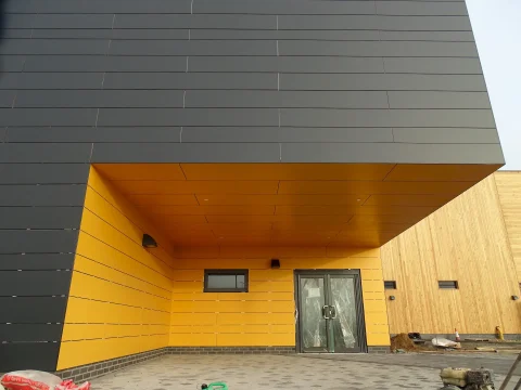 S&G Industrial Roofing installation of a Rockpanel rainscreen facade at Moreton Hall School, featuring a bold black and yellow entrance canopy with precision-fitted panels.