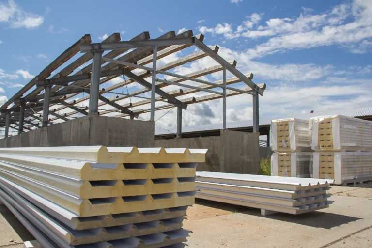 Composite roofing panels stacked at a construction site, ready for installation by S&G Industrial Roofing Ltd. These insulated panels offer a cost-effective, all-in-one roofing solution.