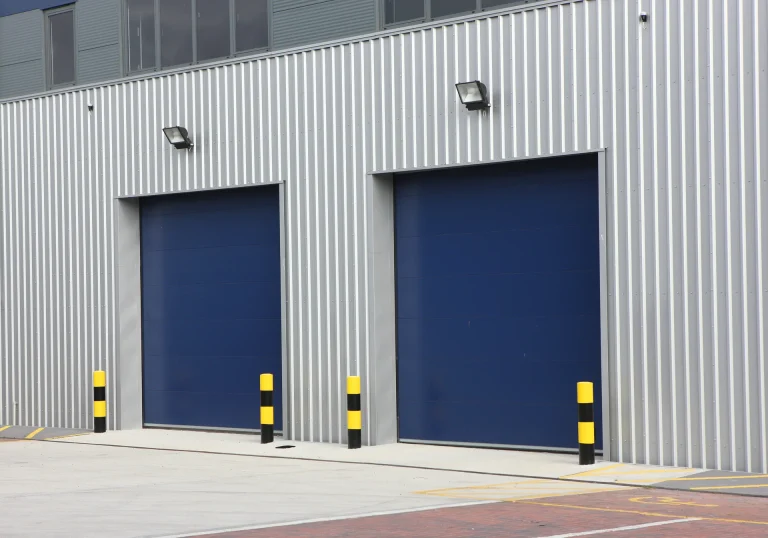 Industrial building with Twin-Skin Built-Up walling featuring a corrugated metal finish and blue roller doors. This system enhances insulation and energy efficiency.